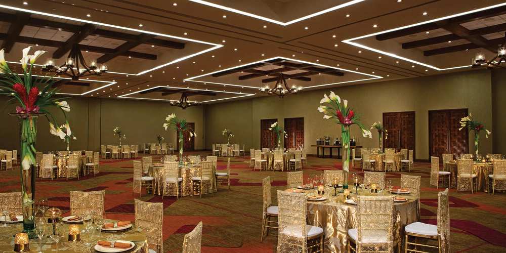 Ballroom wedding reception setup with round tables and elegant lighting at Secrets Akumal Riviera Maya