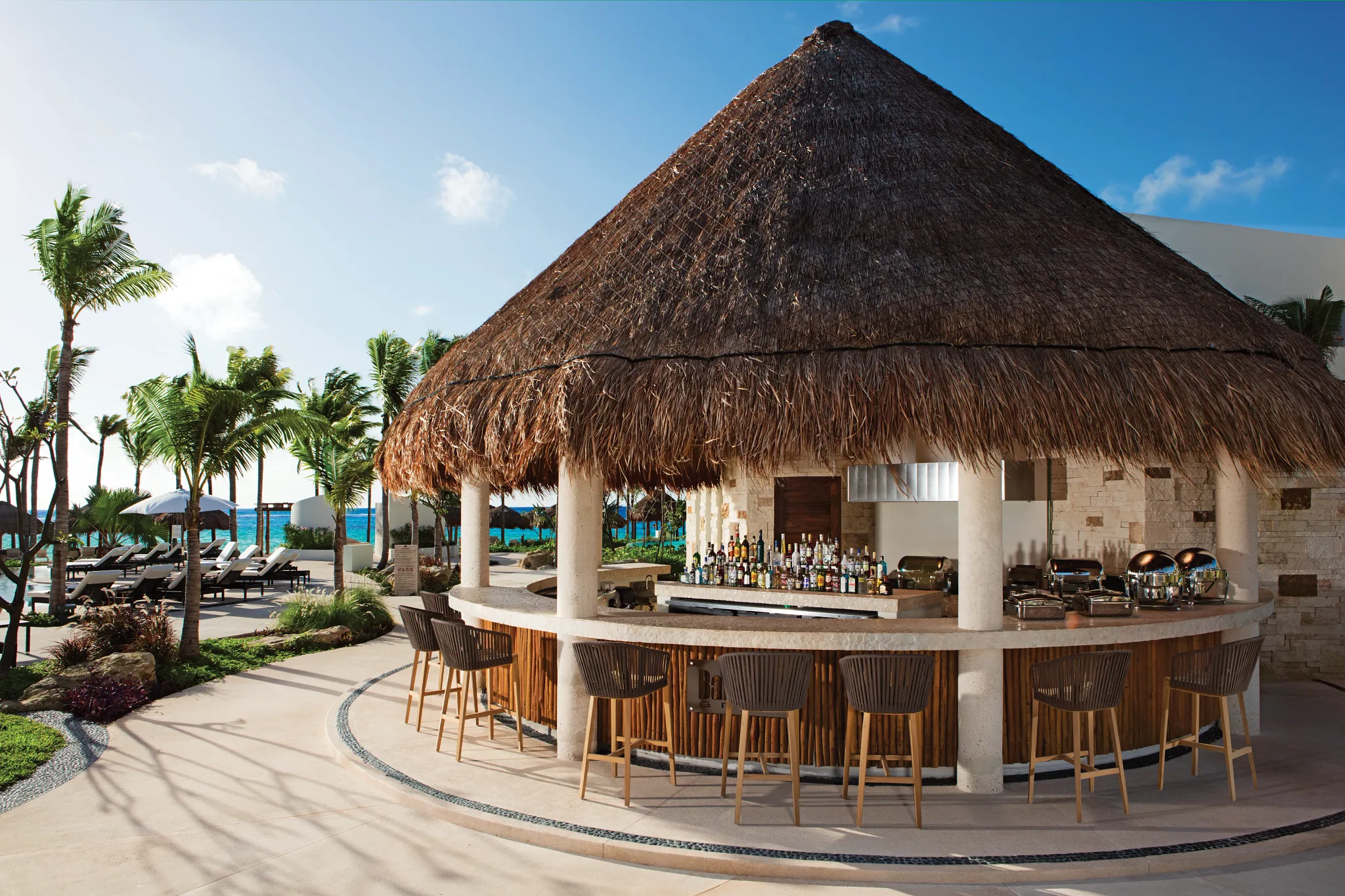 Barefoot Grill at Secrets Akumal Riviera Maya featuring a thatched-roof outdoor bar, casual lunch seating, and tropical resort surroundings near the beach.