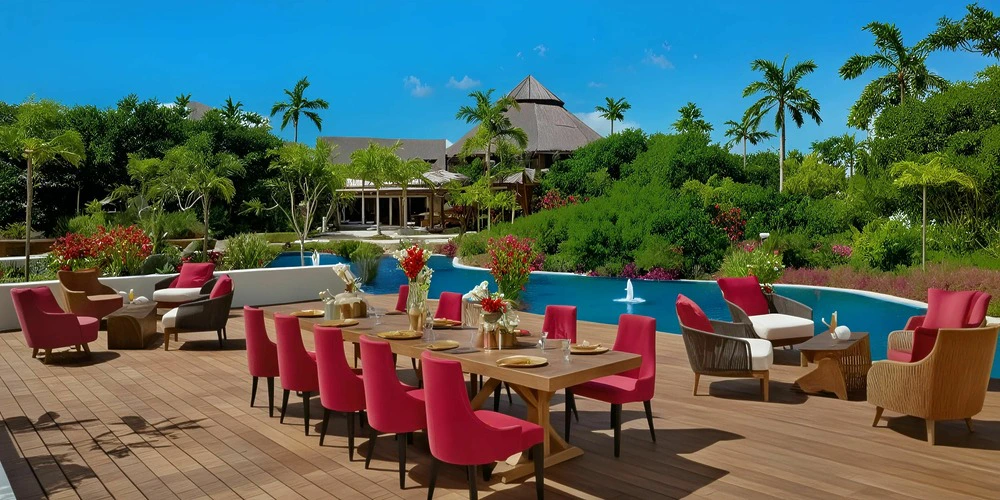 Coco Cafe Deck outdoor event setup with long table seating and lagoon views at Secrets Akumal Riviera Maya