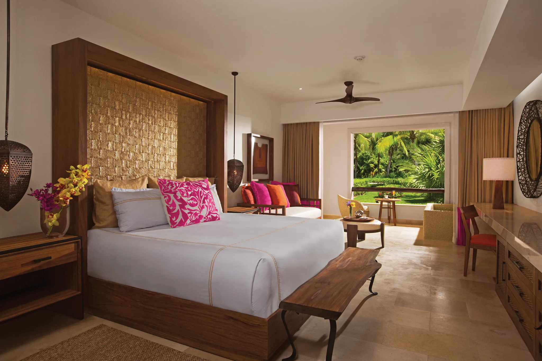 Junior Suite Tropical View with king bed and private balcony at Secrets Akumal Riviera Maya overlooking palm-filled gardens.