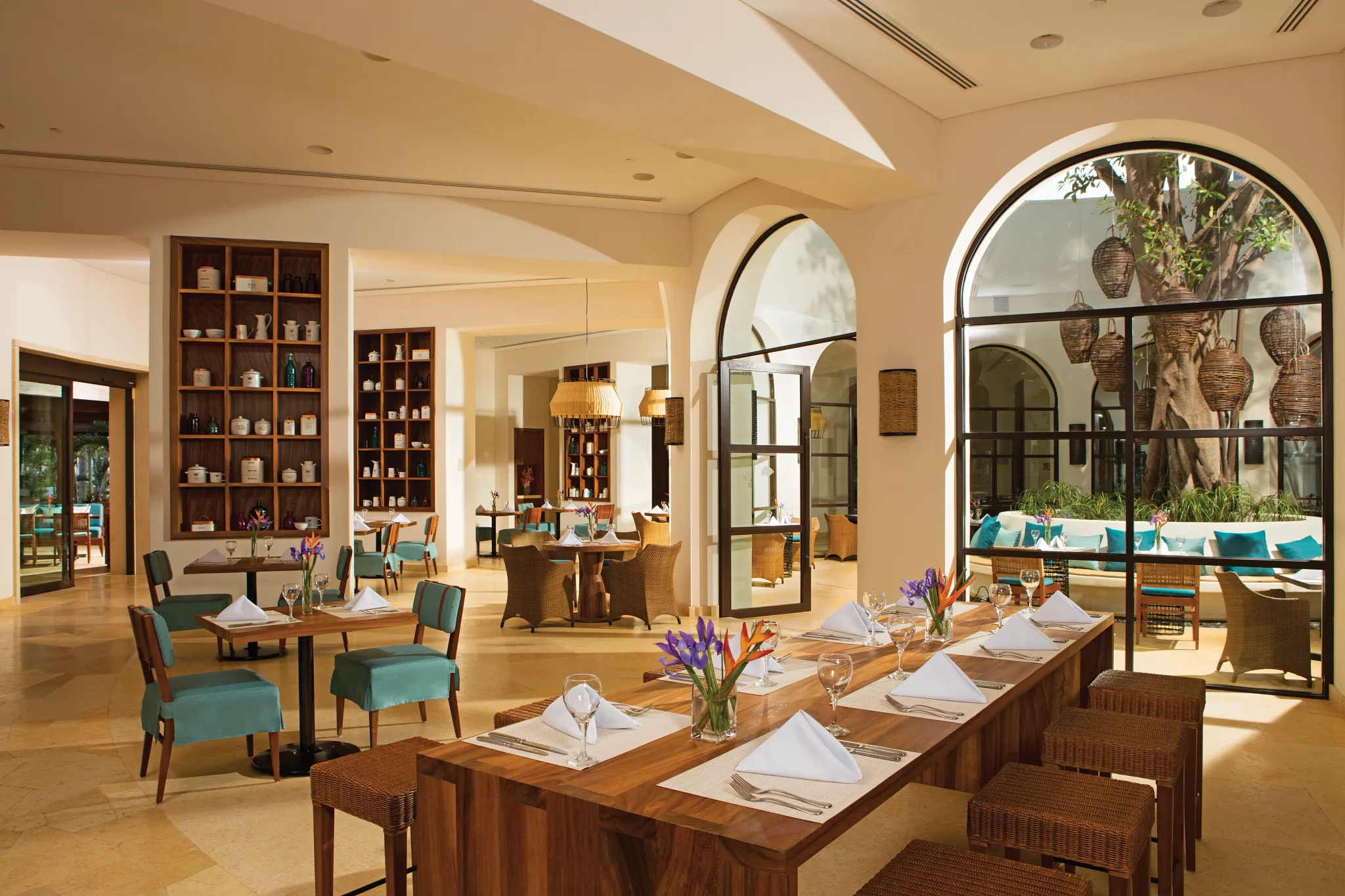 Market Café international buffet at Secrets Akumal Riviera Maya featuring a bright open-air dining room, arched windows, and casual resort seating with tropical accents.