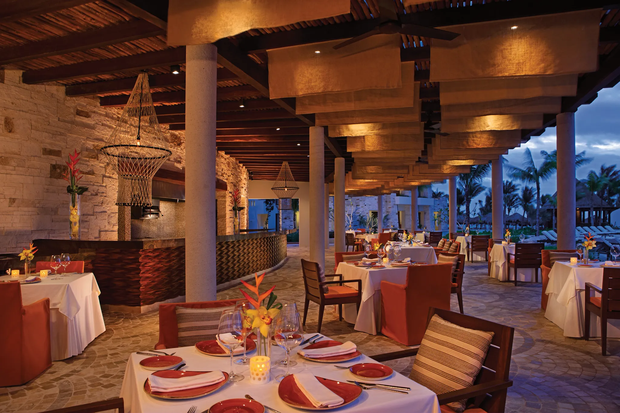 Oceana seafood restaurant at Secrets Akumal Riviera Maya featuring open-air romantic dining with white tablecloth tables, warm lighting, and a seaside evening ambiance.