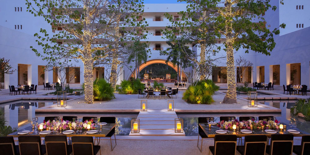 Plaza Akumal courtyard reception setup with candlelit tables and twinkling trees at Secrets Akumal Riviera Maya