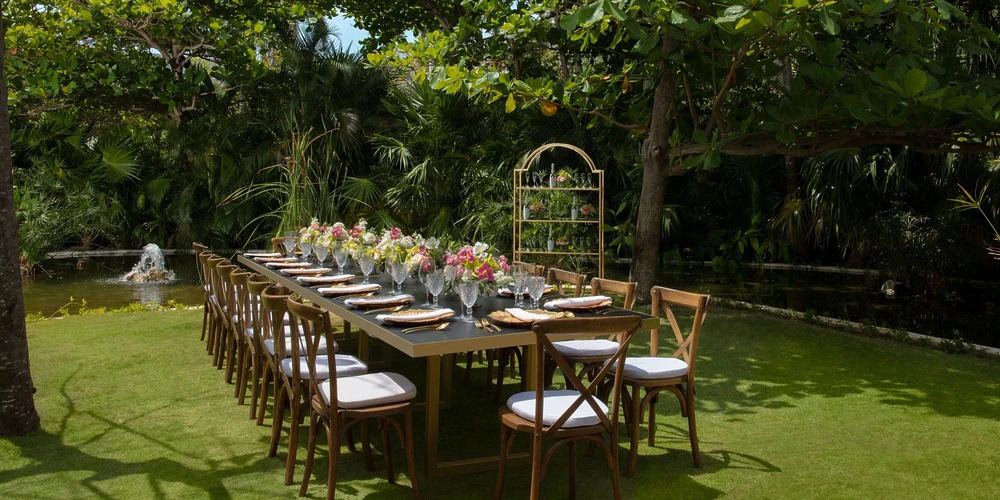 Secret Garden outdoor reception setup with long table, floral décor, and lush greenery at Secrets Akumal Riviera Maya